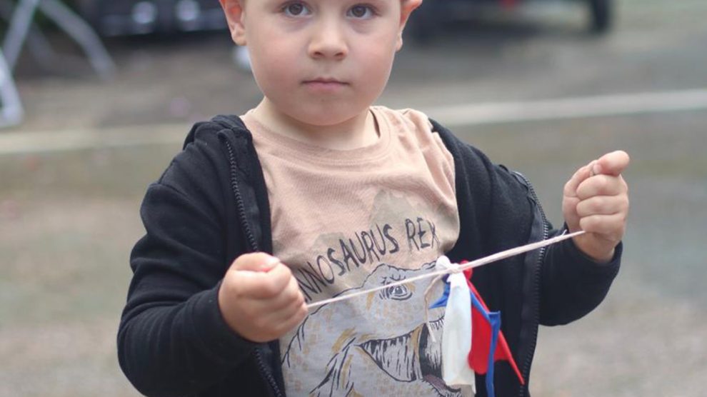 A young child wears a paper crown