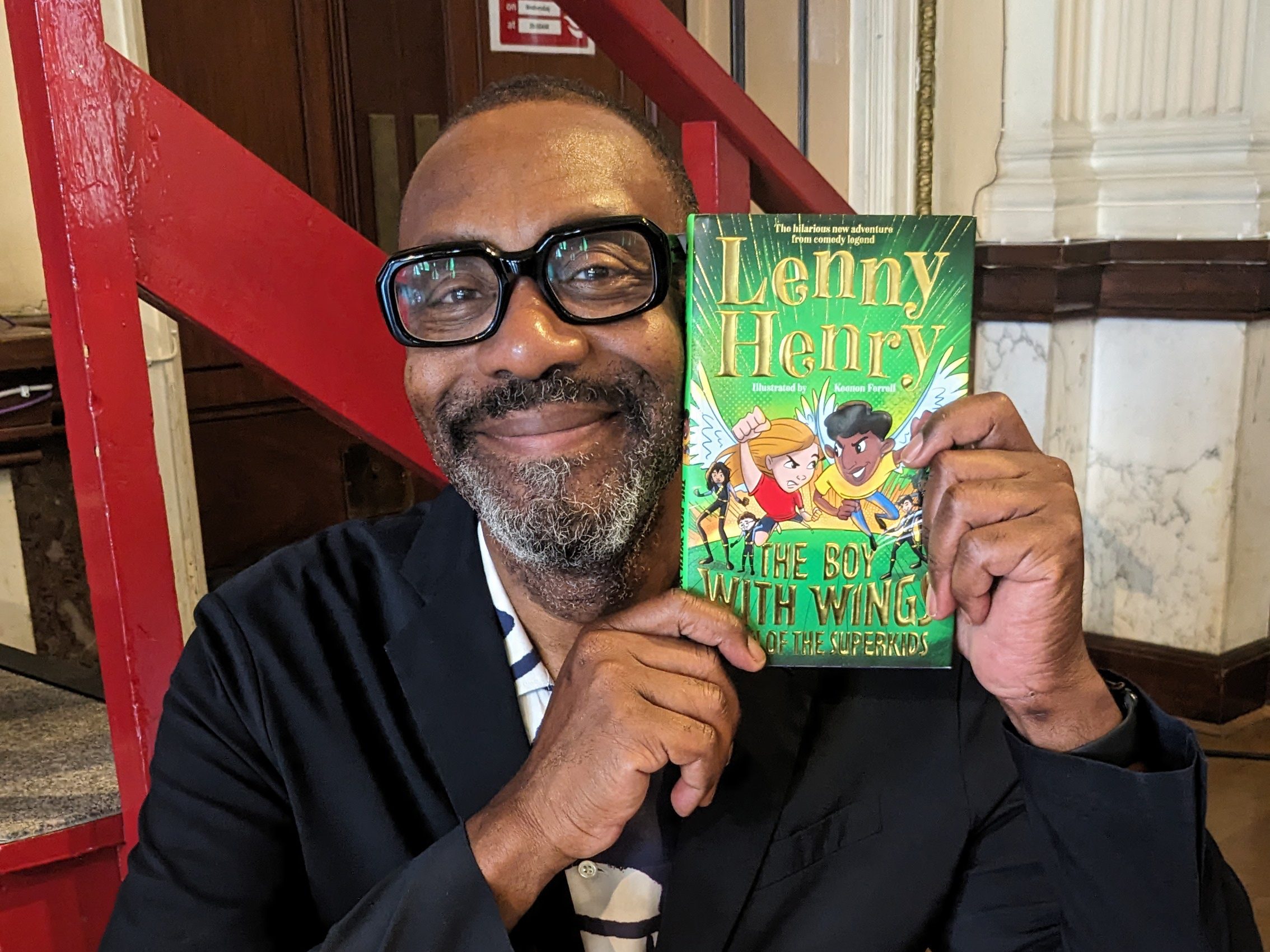 Sire Lenny Henry holds up a copy of his new book