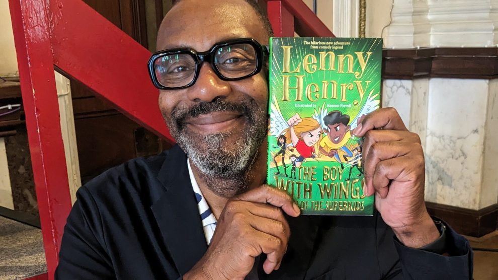 Sire Lenny Henry holds up a copy of his new book
