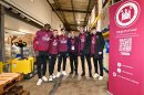 Young men in sports kit stand next to a large sign reading 'Irons Supporting foodbanks'
