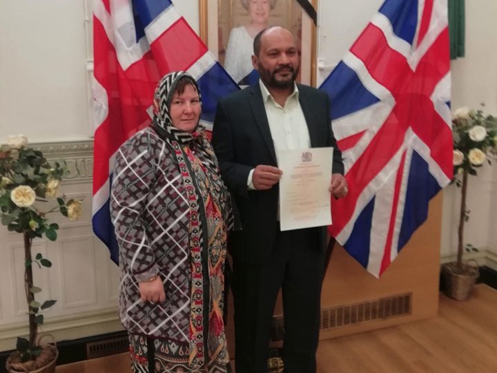 A couple stand before two union jack flags