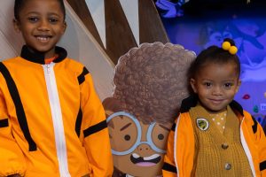 Two children stand with a cartoon child astronaut