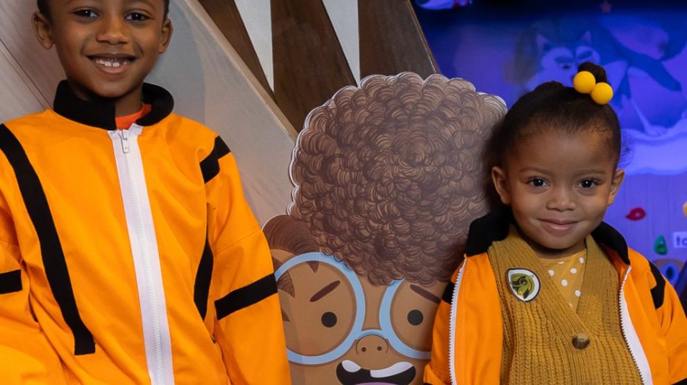 Two children stand with a cartoon child astronaut