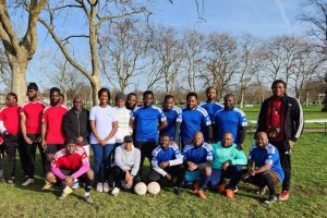 A group of people pose with footballs in a park