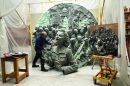 An artist works on a huge disc with a relief of Dame Vera Lynn