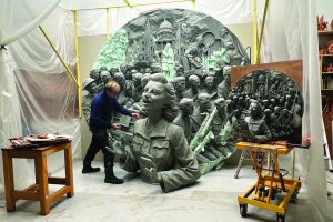 An artist works on a huge disc with a relief of Dame Vera Lynn