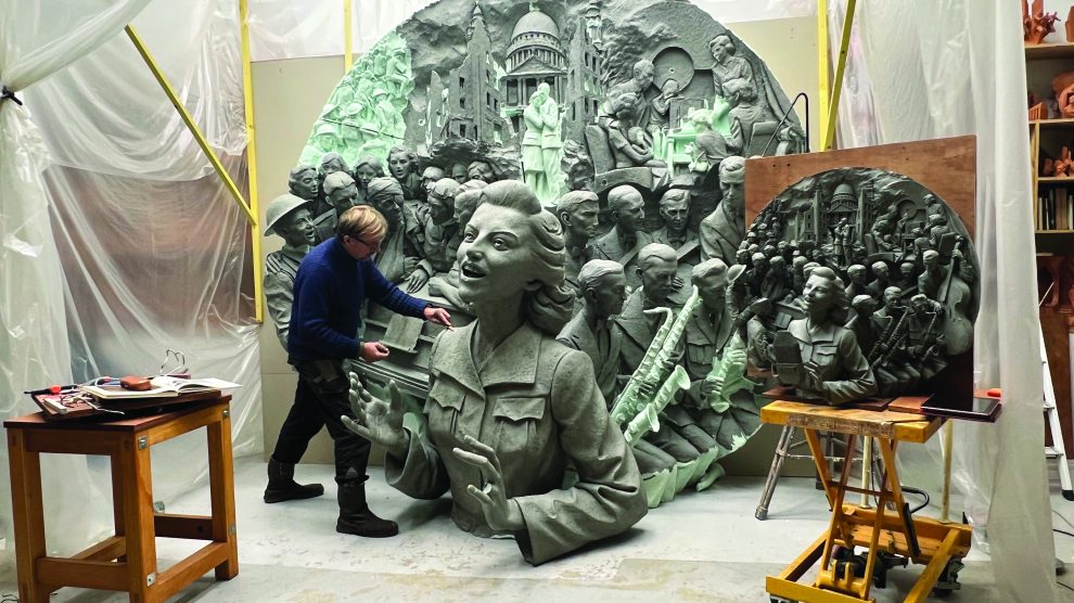 An artist works on a huge disc with a relief of Dame Vera Lynn