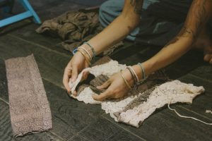 a person works on a piece of reclaimed fabric