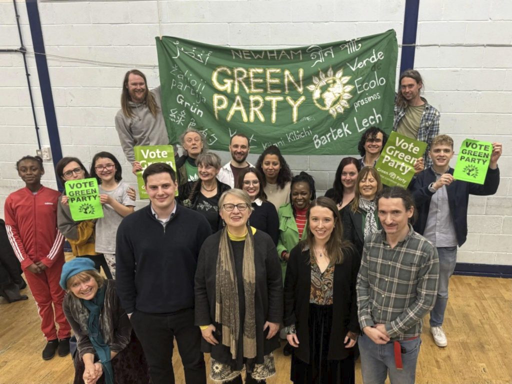 a group of people pose before a banner reading 'green party'