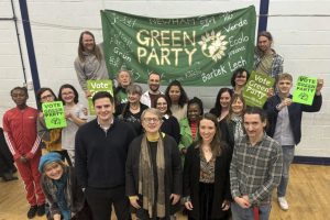 a group of people pose before a banner reading 'green party'