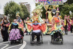 A group of people using wheel chairs dressed in brightly coloured costume