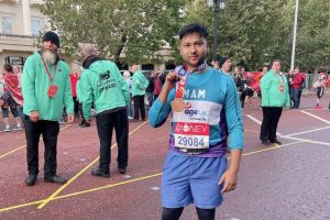 Cllr Haque at the finish of a marathon holding a medal