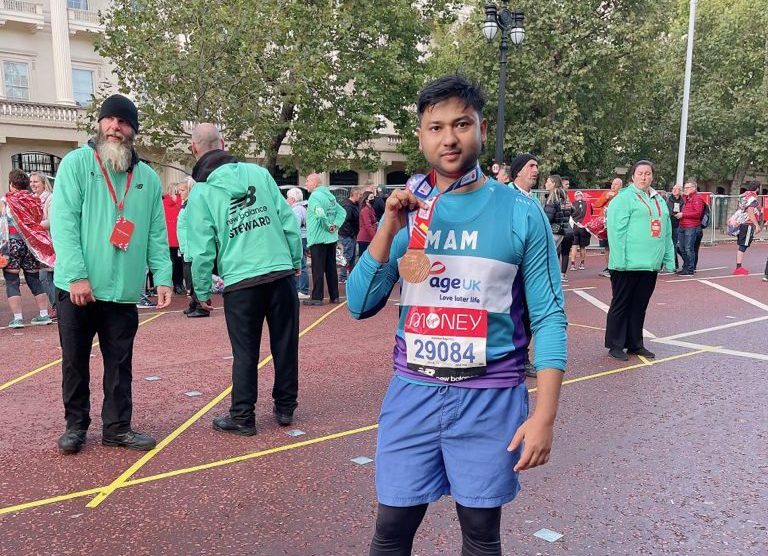 Cllr Haque at the finish of a marathon holding a medal