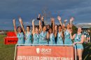 A group of netballer players celebrate arms aloft