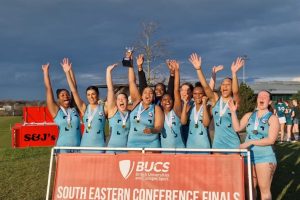 A group of netballer players celebrate arms aloft