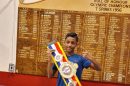 A young person holds up a boxing title belt