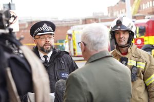 A firefighter and a police officer speak to meambers of the public