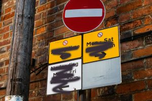 parking ristriction signs with black spray paint obscuring them