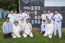 cricketers pose by a circket scoreboard