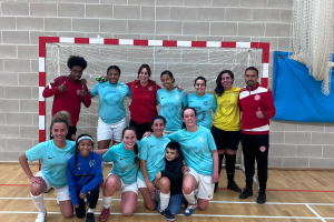 A team poses in front of a futsal goal