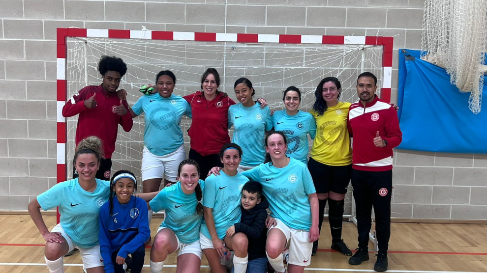 A team poses in front of a futsal goal