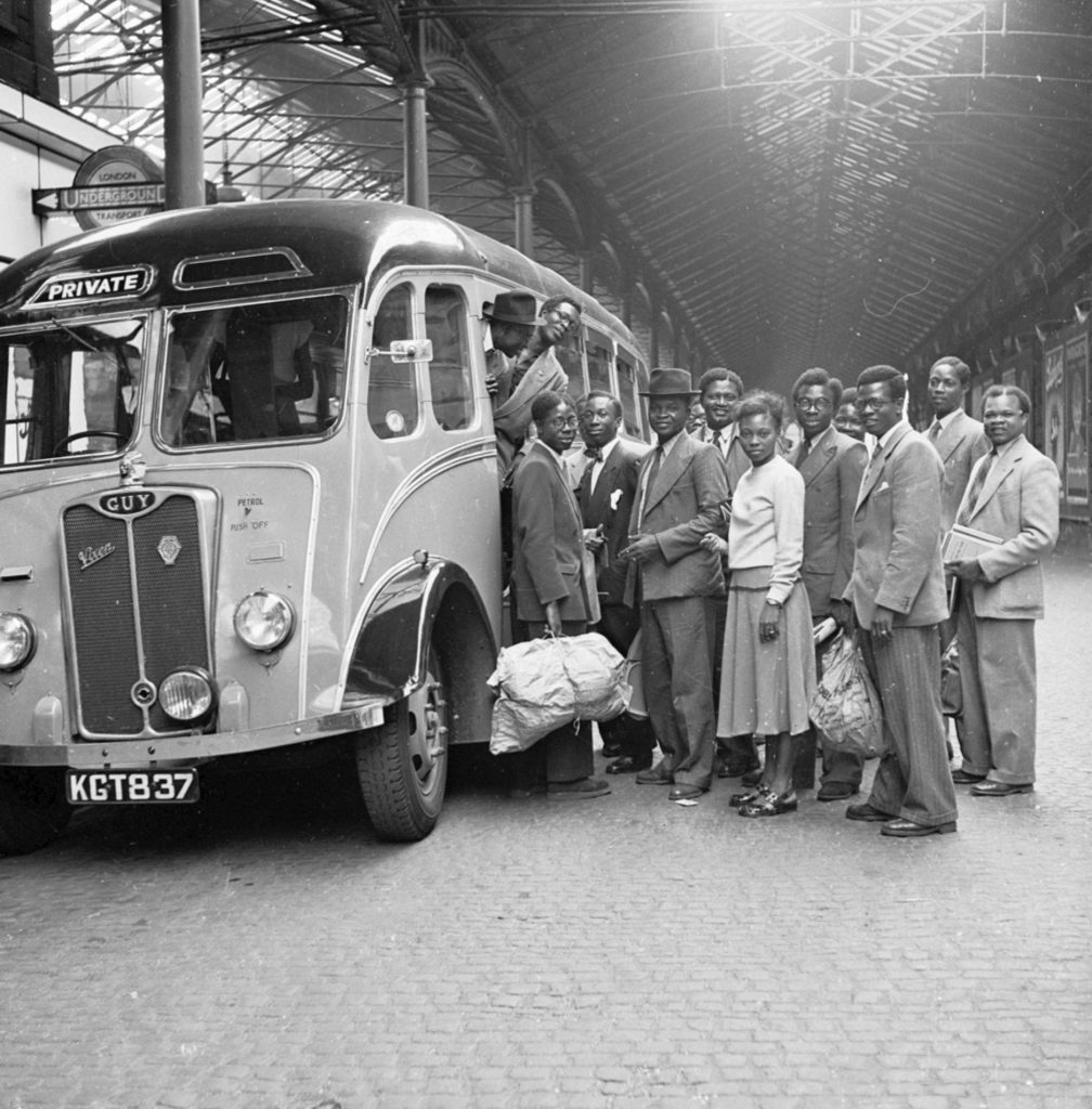 people stand by a bus in a black and white photo