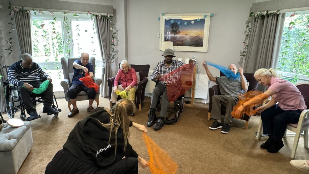 People seated move coloured silks through the air
