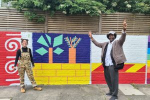 People stand in front of a bright mural