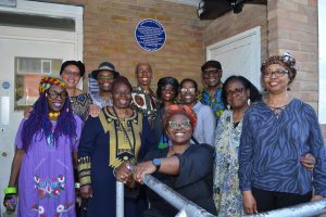 a group of people pose by an unveiled blue plaque