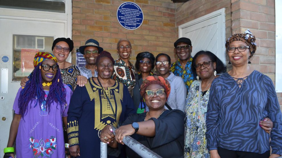 a group of people pose by an unveiled blue plaque