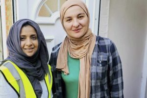 Two women distribute Qubani food parcels