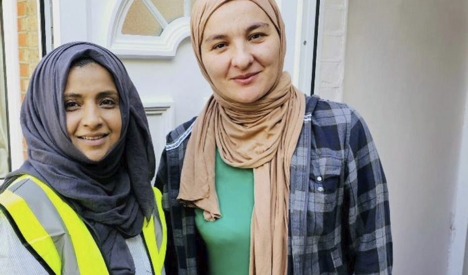 Two women distribute Qubani food parcels