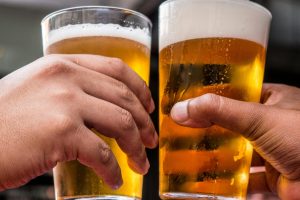 Two pints of beer raised in cheers