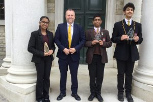 students in school uniform stand proudly with awards