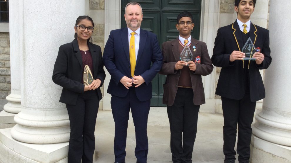 students in school uniform stand proudly with awards