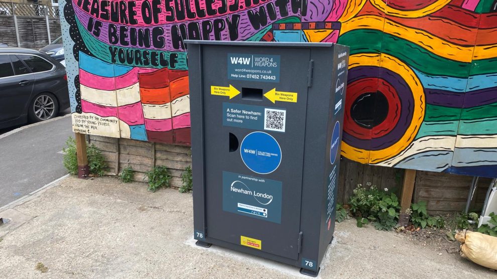 A metal knife amnesty bin in front of a brightly coloured mural
