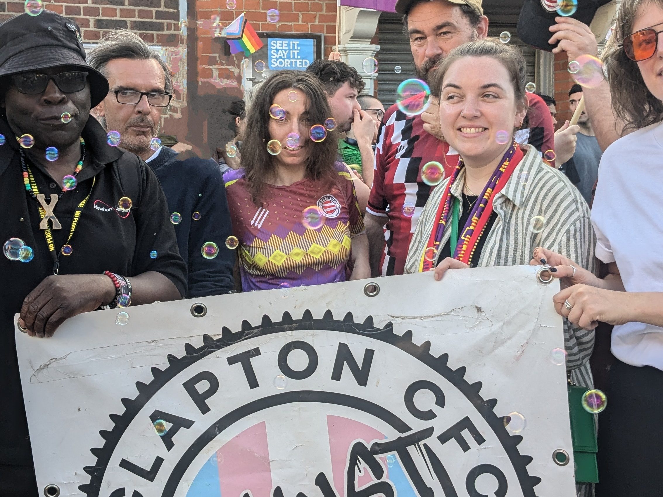 a group of people hold a banner that says 'Clapton FC against Terfs'