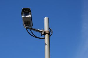A video camera on a pole in front of a blue sky