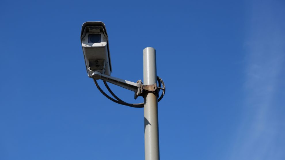 A video camera on a pole in front of a blue sky