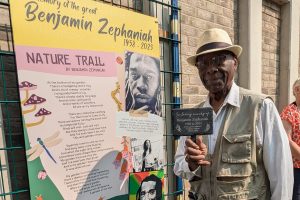 A person stands by a display board with details of Banjamin Zephaniah's life