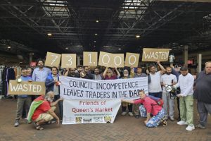 A group of people hold a banner reading 'council incompetence leaves traders in the dark'