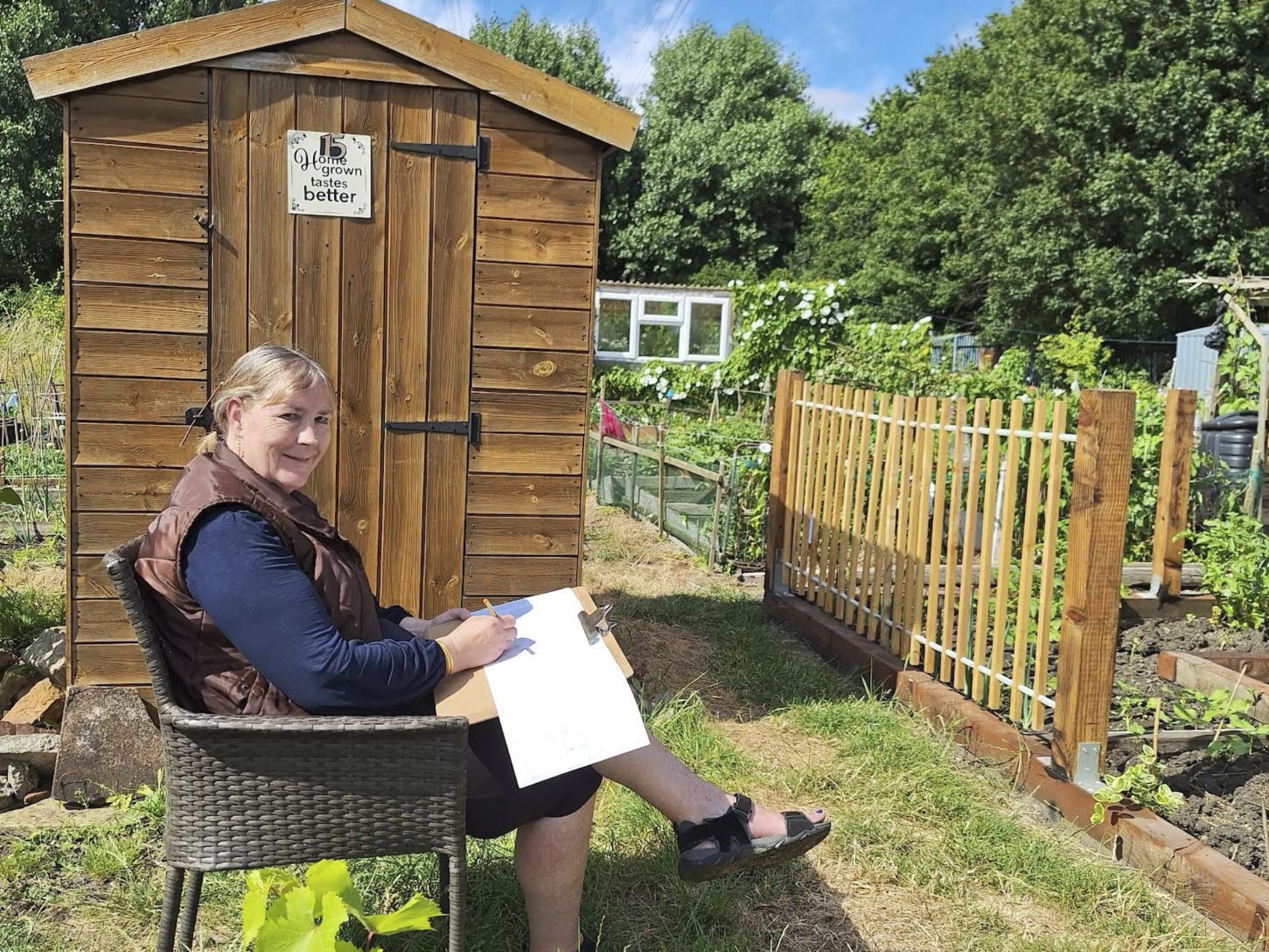 A person with an open pad sits in a sunny allotment
