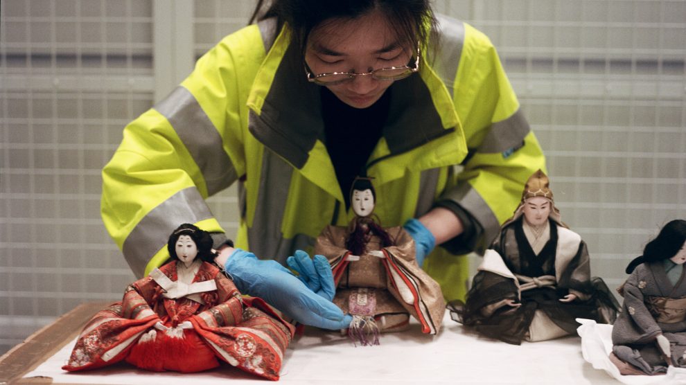 worker placing the dolls in V&A museum