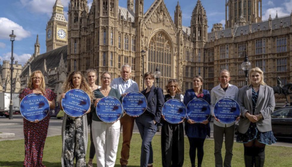 Bereaved relatives with blue plaques outside of the palace of Westminster