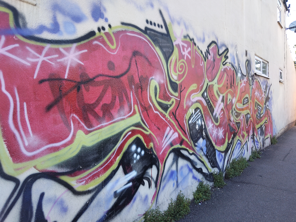 A wall covered in brightly coloured graffiti tags.