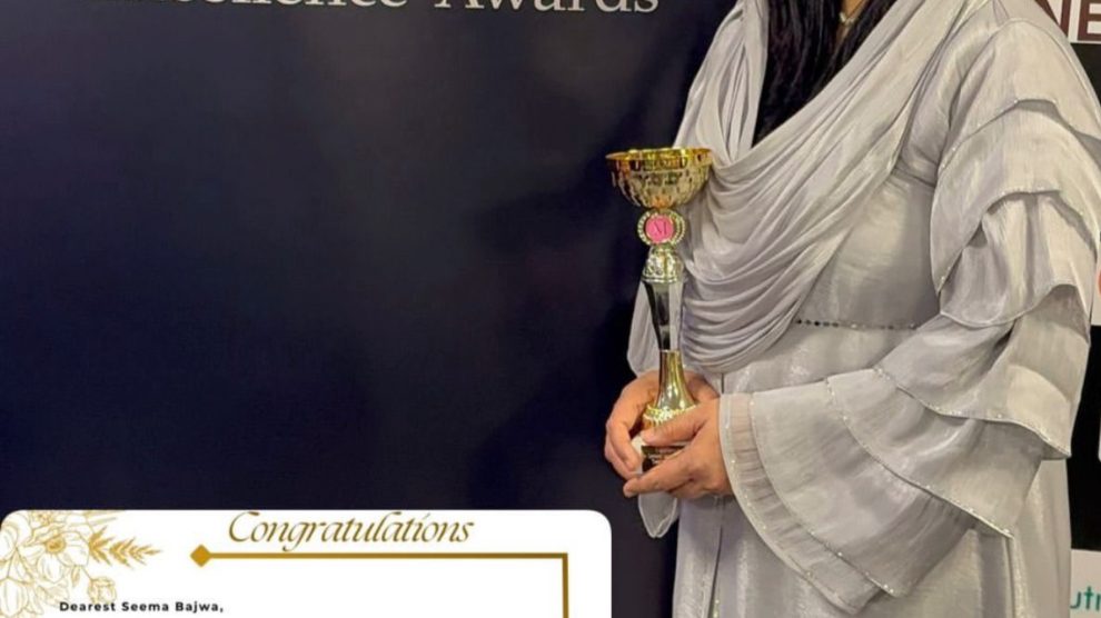 A woman holding a trophy standing in front of an awards sign