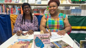 Two women sitting behind a table covered in books