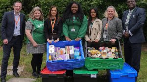 A group of people pose with collected food bank donations