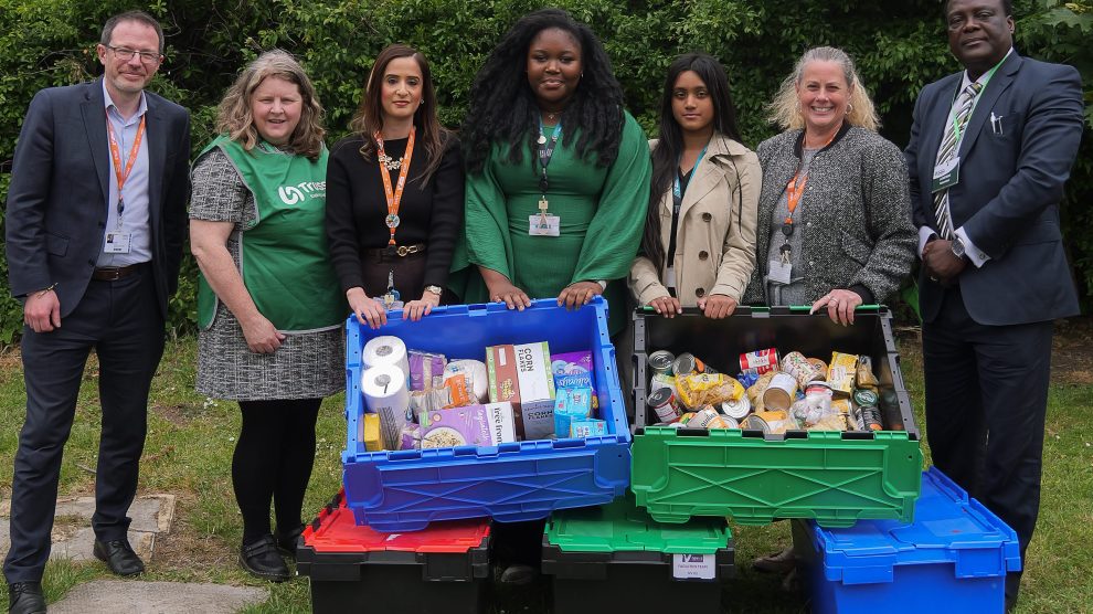 A group of people pose with collected food bank donations