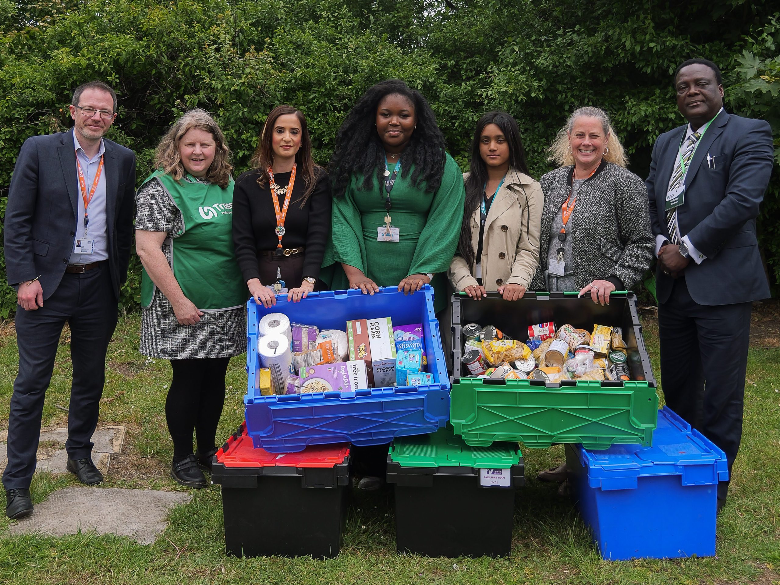 A group of people pose with collected food bank donations